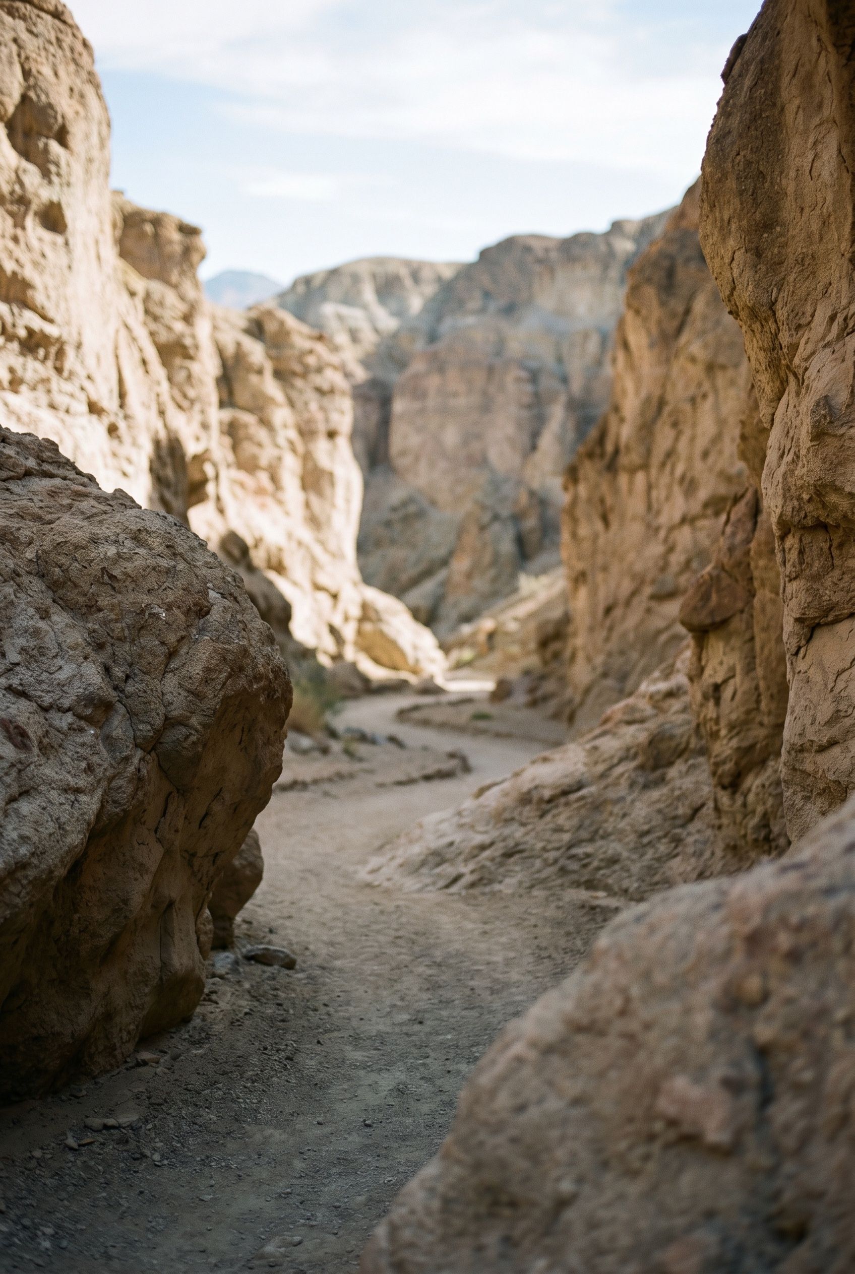 A desert slot canyon in late afternoon, warm sandstone walls carved with deep shadow
