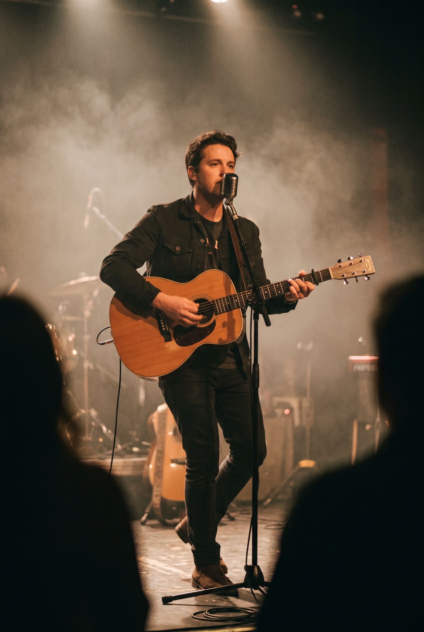 A musician playing acoustic guitar in a dark club under magenta and teal stage light