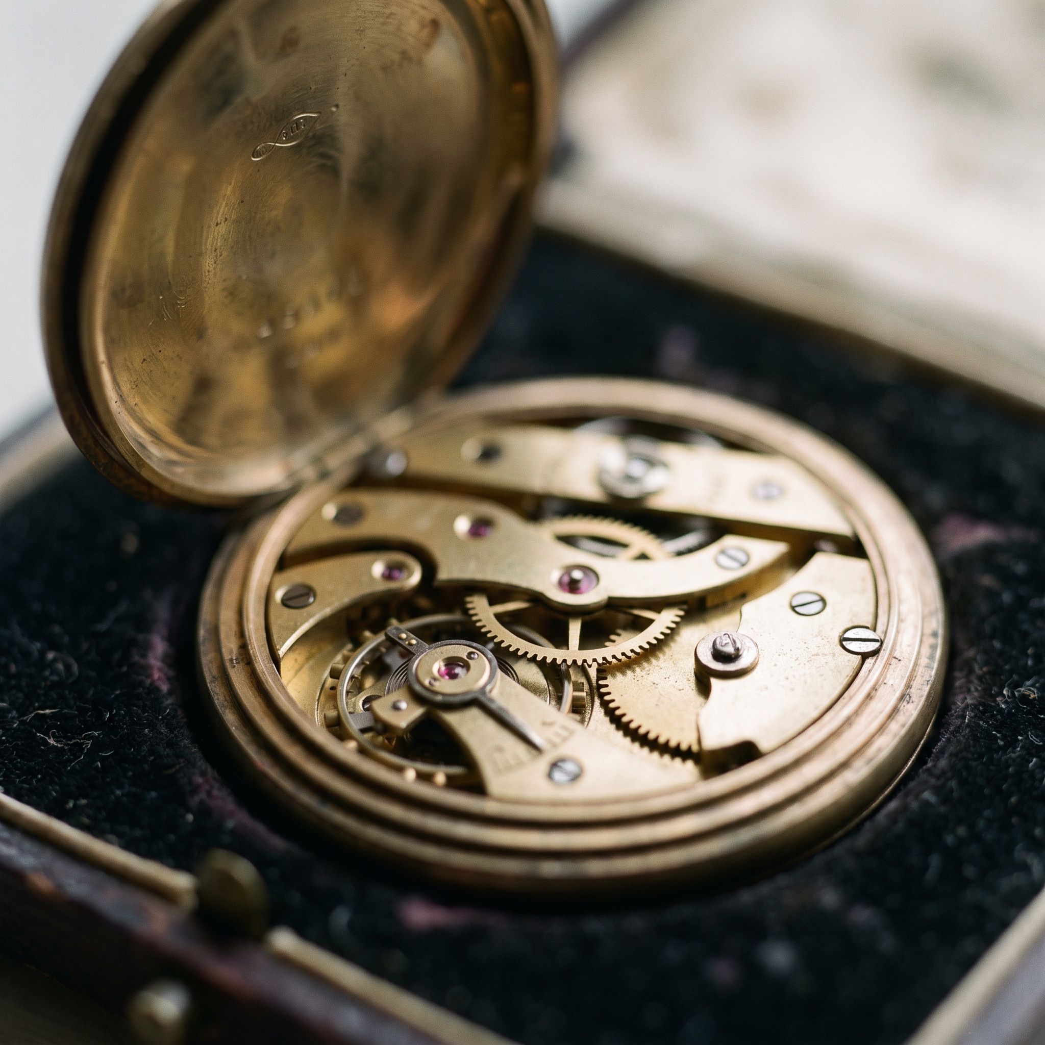 Macro photograph of an open antique pocket watch showing its brass gears
